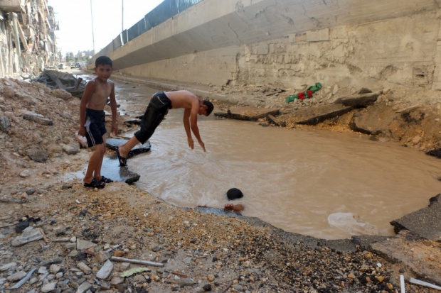 Fëmijët sirianë bëjnë not në gropa të krijuara nga raketat